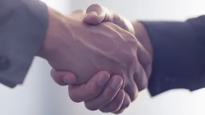 A close-up of two people in business suits shaking hands.
