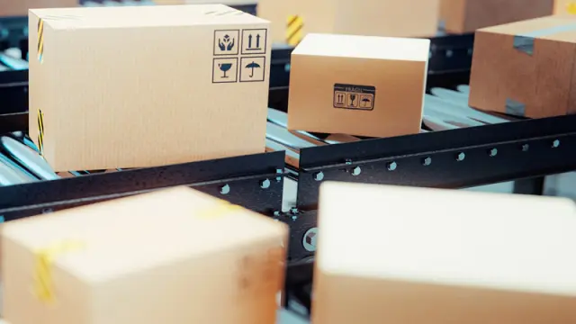Cardboard boxes with shipping labels moving along a warehouse conveyor belt system.