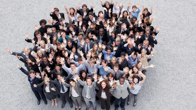 High-angle view of a large, diverse group of business people looking up, smiling, and waving.