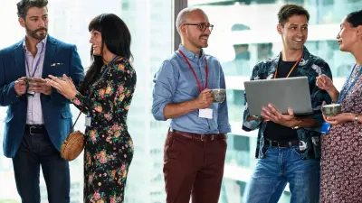 A diverse group of professionals are talking to eachother in small groups during a coffee break.