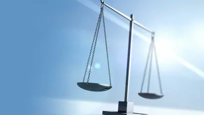 The scales of justice against a bright blue sky with a lens flare.