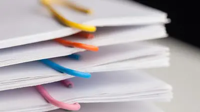 A close-up of a stack of documents organized into sections with colorful paperclips.