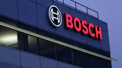 A large, illuminated red and white Bosch logo on the side of a modern office building at dusk.